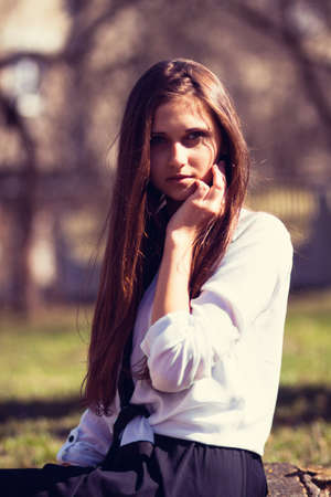 Beautiful girl sitting on a tree stumpの写真素材