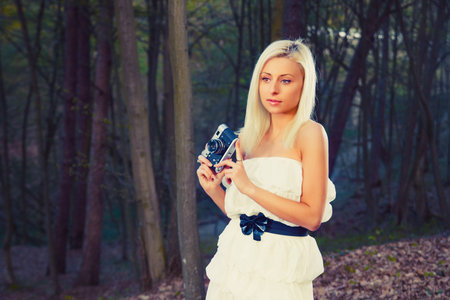 Beautiful adult girl with retro photo camera in a forestの写真素材