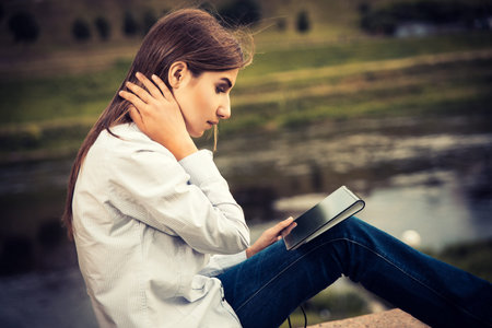 Beautiful young girl using digital tablet outdoors