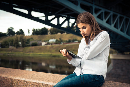 Beautiful young girl using digital tablet outdoorsの写真素材