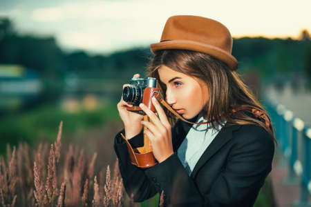 Beautiful hipster girl shooting with retro cameraの写真素材