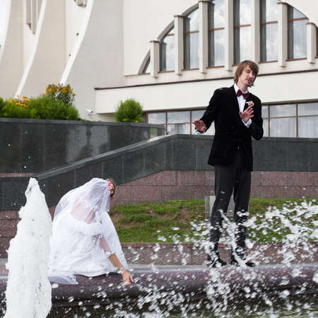 Beautiful bride and groom stand near fountainの写真素材