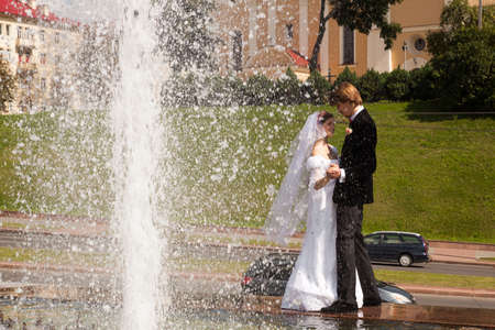 Beautiful bride and groom stand near fountainの写真素材