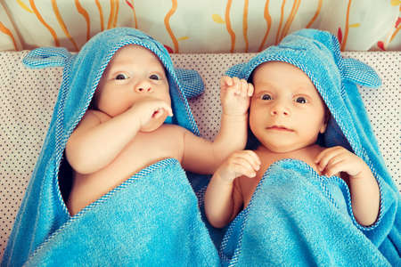 Two beautiful twins laying wrapped in a towelの写真素材