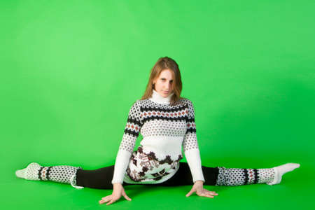 Beautiful young woman sitting on green backgroundの写真素材