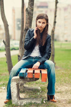 Beautiful young brunette girl sitting alone outdoorsの写真素材