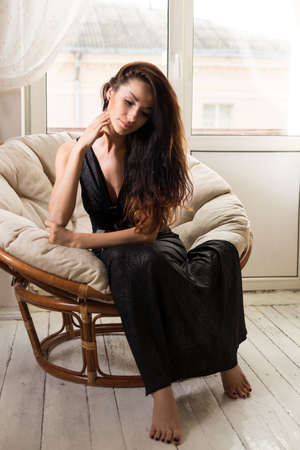Sexy girl sitting on arm chair near the windowの写真素材