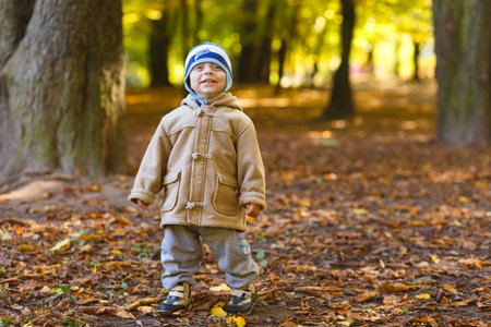 Beautiful happy boy walking on autumn parkの写真素材