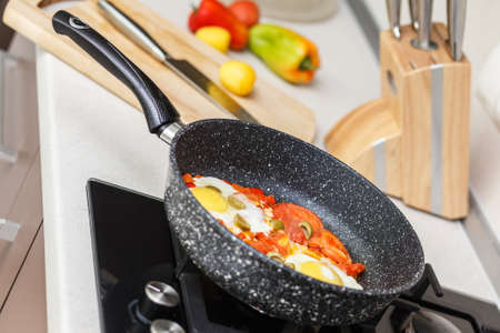 Frying pan with eggs and tomatoesの写真素材