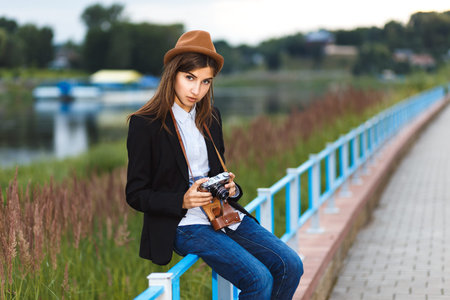 Beautiful hipster girl shooting with retro camera
