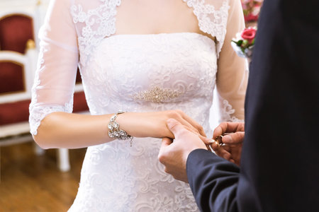 Hands with rings Groom putting golden ring on bride's finger during wedding ceremony
