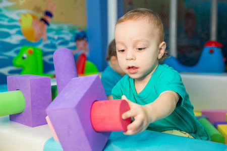 little boy playing with cubes in the entertainment centerの写真素材