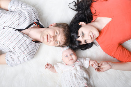 Young beautiful family of 3 persons Mum, Dad and little daughter posing in the studio