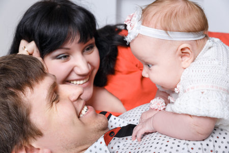 Young beautiful family of 3 persons Mum, Dad and little daughter posing in the studio