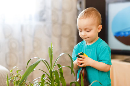cute baby boy irrigating home plants indoorsの写真素材