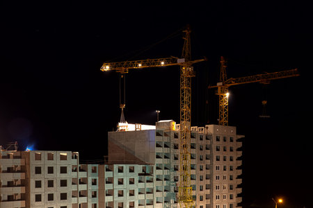 high buildings under construction with cranes at night in motion