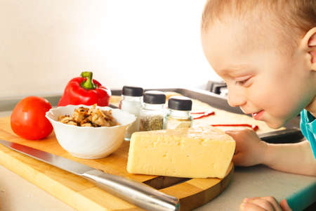 Small boy making pizza with ingredients on the kitchenの写真素材
