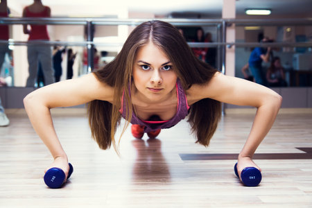 fitness woman working out doing push-ups strength training in the gym