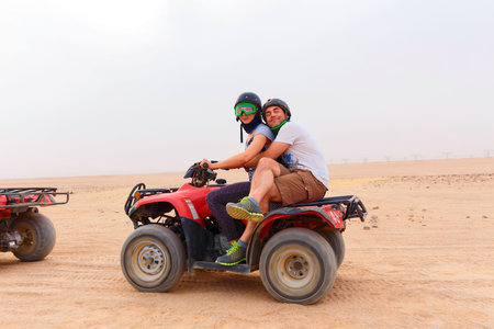 Young couple riding sand ATV and having fun
