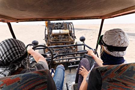 Young couple riding buggy car in desert and having fun
