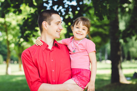 father and daughter.Young man and beautiful little girl in summer parkの写真素材