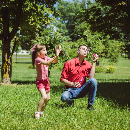 A dad and his daughter are making bubbles in the parkの写真素材
