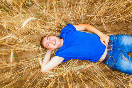 Handsome guy lying in a wheat field and looks upの写真素材