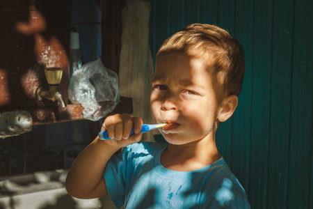 Boy cleaning teeth on wooden blue background