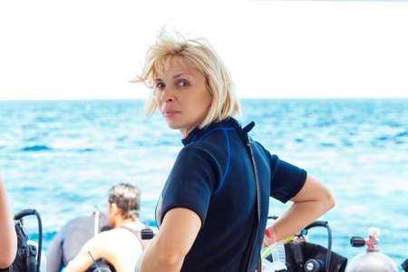 Back side of calm diver woman standing on yacht deckの写真素材