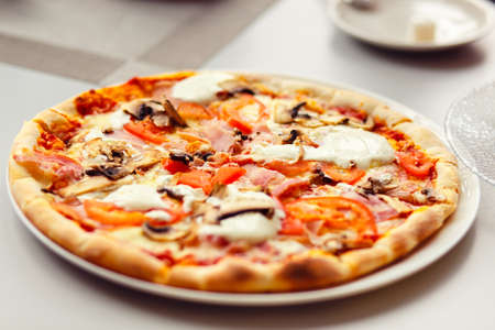 Pizza with Mozzarella Cheese, Fresh Tomato and Mushrooms. Served at Restaurant Tableの写真素材