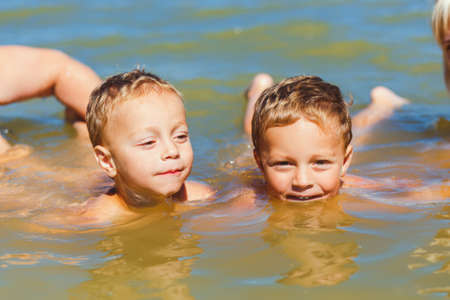 Twin brothers learn to swim under the supervision of parentsの写真素材