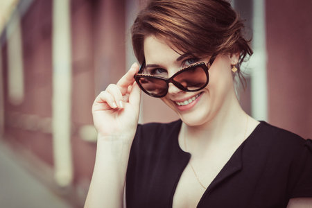 Close-up of beautiful brunette model in stylish sunglasses. Young pretty female posing outdoorsの写真素材