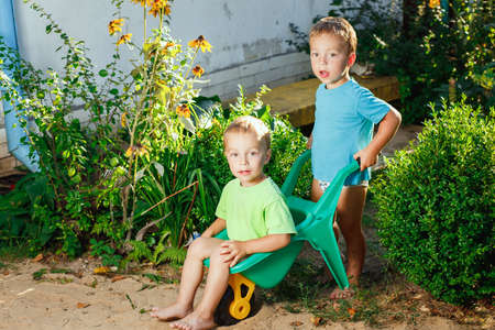 Twin brothers playing using a garden cartsの写真素材