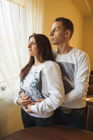 Couple standing by window in his home.の写真素材