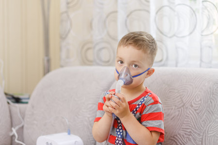 Small boy does therapeutic inhalation using a nebulizerの写真素材