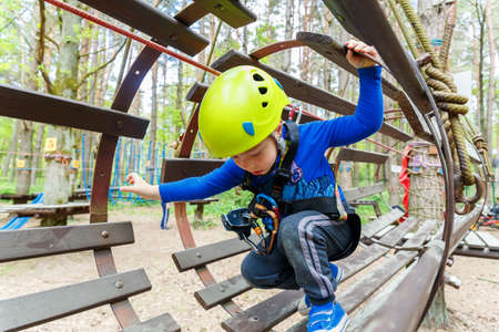 Portrait of 3 years old boy wearing helmet and climbing. Child in a wooden obstacle course in adventure playgroundの写真素材