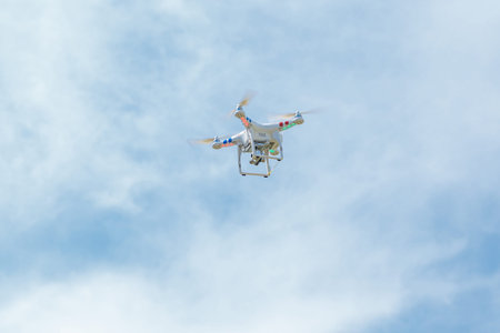 white drone hovering in a blue sky