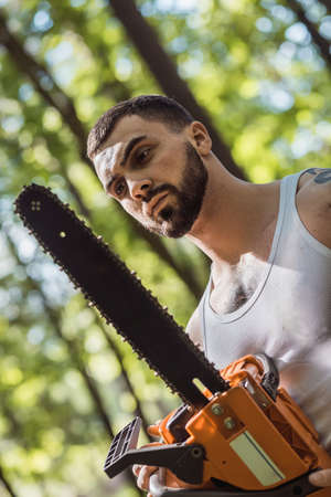 portrait of aggressive muscular male lumberjack, woodworker with chainsaw in hand, posingの写真素材