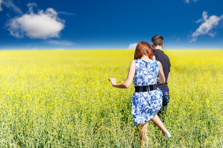 Image of happy couple running in yellow meadow at summerの写真素材