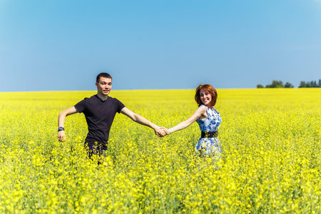 Image of happy couple running in yellow meadow at summerの写真素材