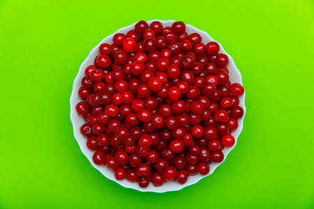 Set of beautiful red cherry in a glass dish on green background.の写真素材