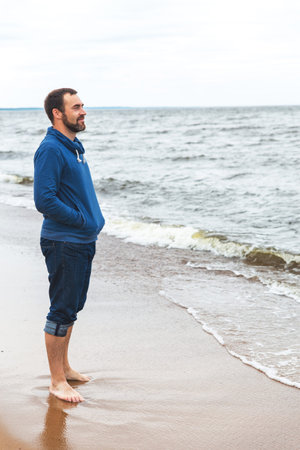 A young man stands on the seashore and looksの写真素材