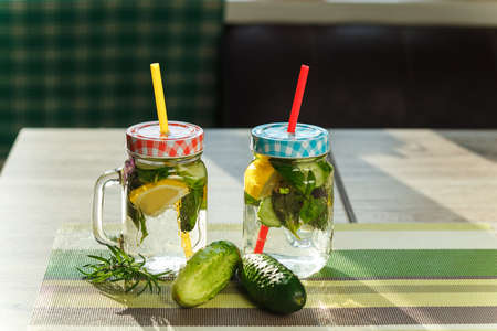 Two retro glass jars of lemonade with cucumber and lemon on tableの写真素材