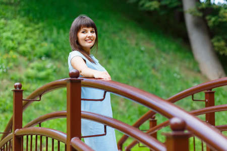 Beautiful young woman standing on the bridge in the parkの写真素材