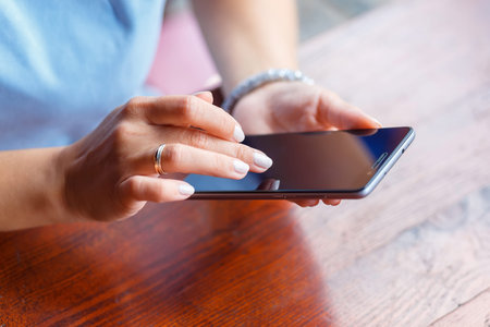 A young woman is using her smart phone at a table outside