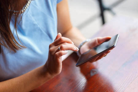A young woman is using her smart phone at a table outside