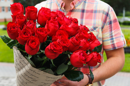 A man carrying a huge bouquet of red roses in gift girlの写真素材