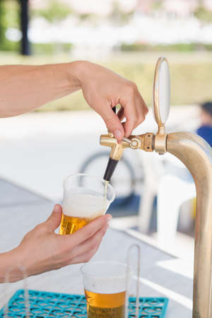 Draft beer pour in a plastic cup from the crane. Selective focus.の写真素材