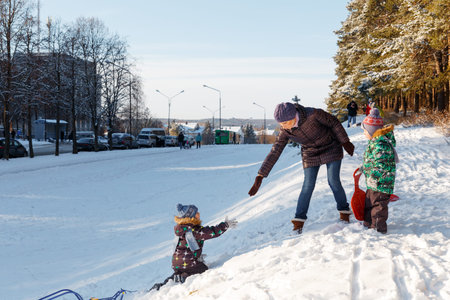 Happy young woman with two children on a sled on winter walkの写真素材