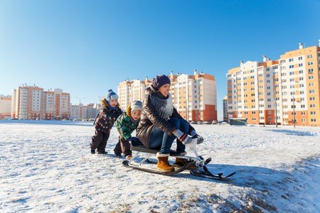Happy young woman with two children on a sled outdoorsの写真素材